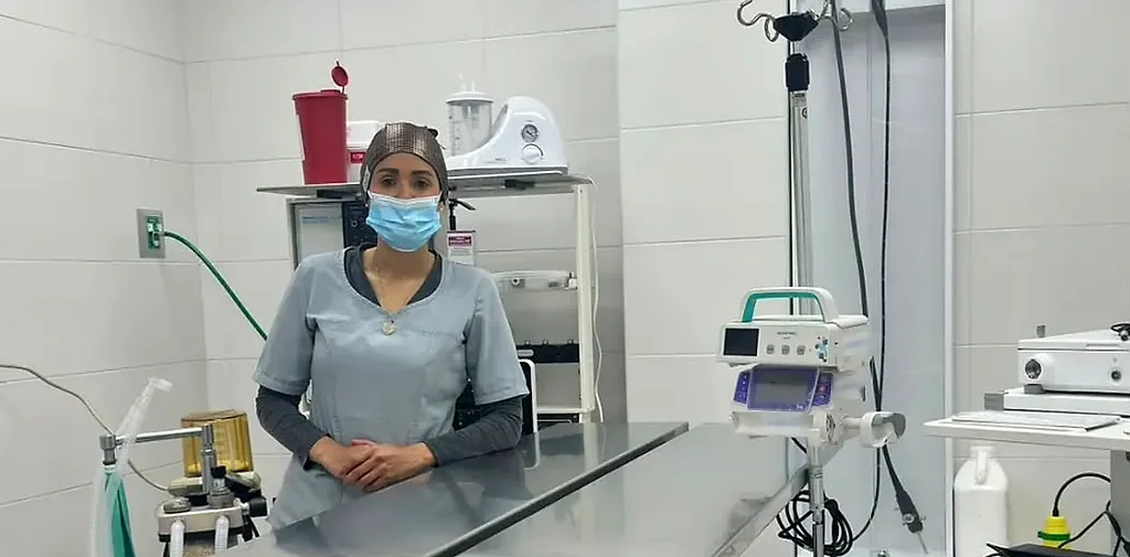 La Dra. Yoneidys Barrada de pie detrás de la mesa de acero de su consultorio, con los equipos a su alrededor